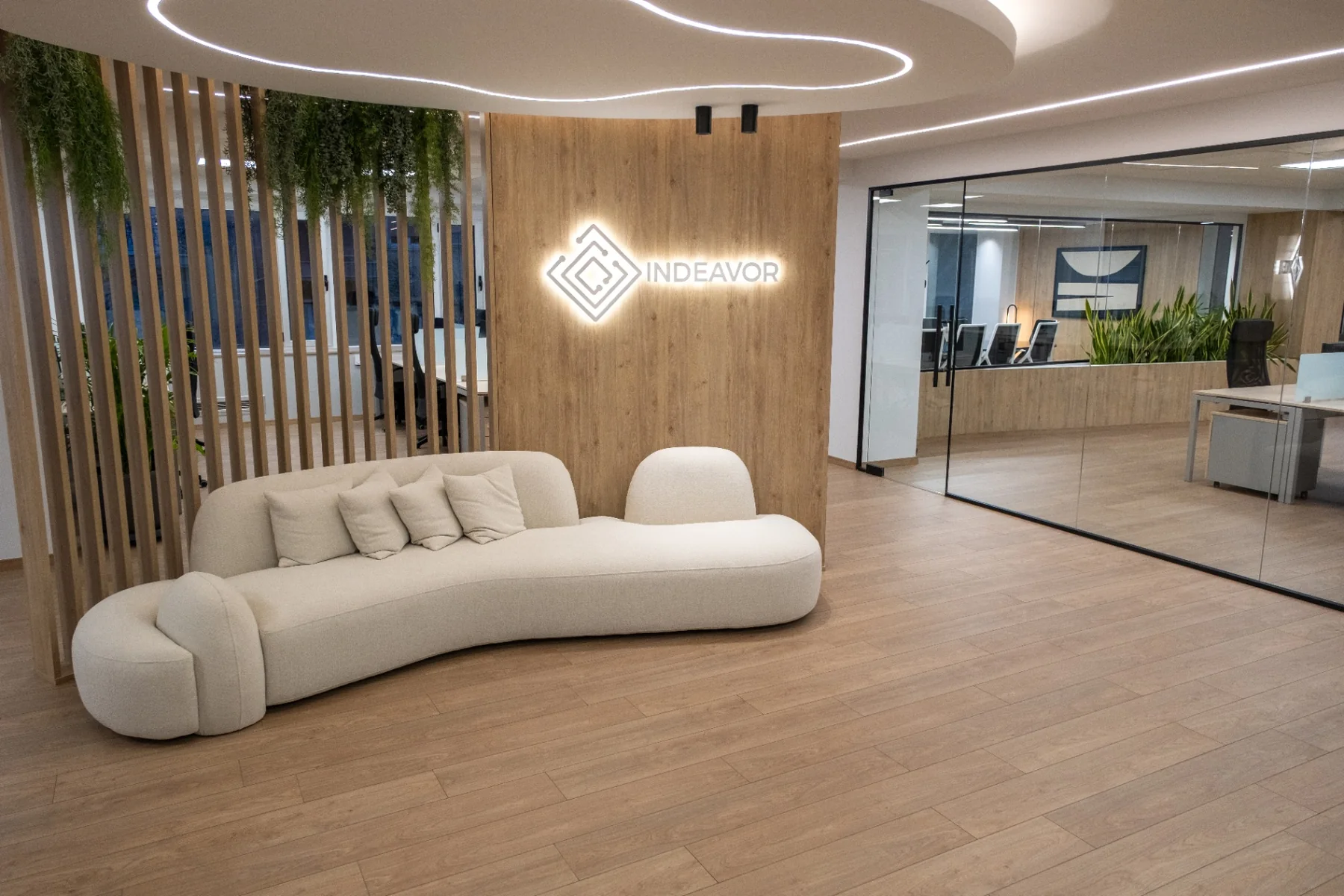 Reception των γραφείων Indeavor με καμπύλο καναπέ, ξύλο και φωτεινή σήμανση